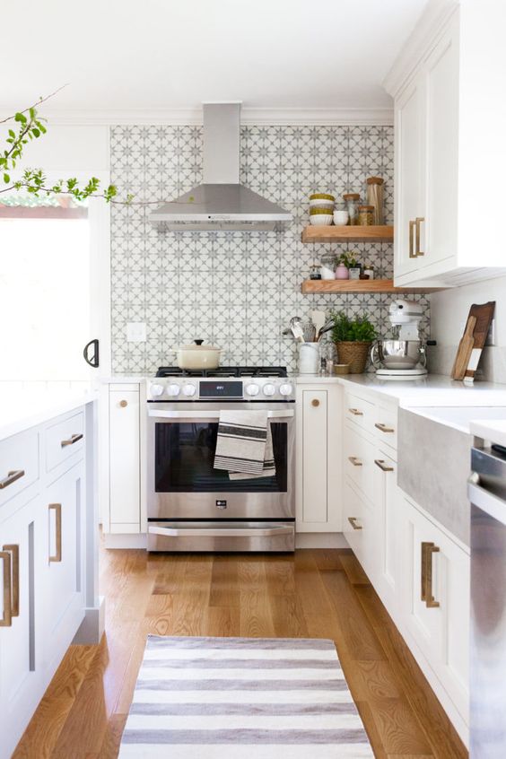 a pretty neutral kitchen with a printed tile backsplash, brass handles, potted greenery and woven planters