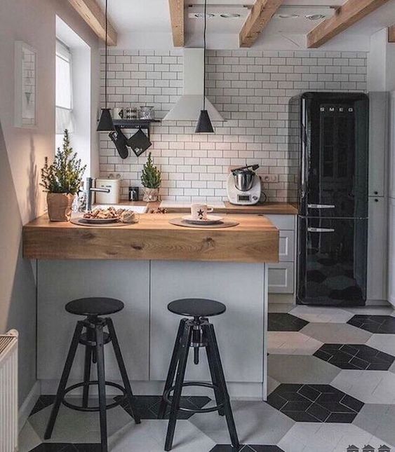 a small Scandinavian kitchen in black, white and grey, with butcherblock countertops and a white tile backsplash and pendant lamps