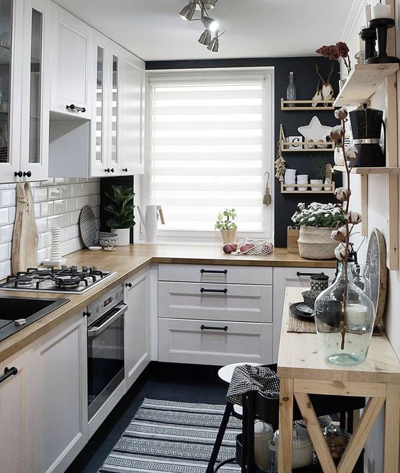 a small Scandinavian kitchen with a white tile backsplash, butcherblock countertops, open shelves and black walls