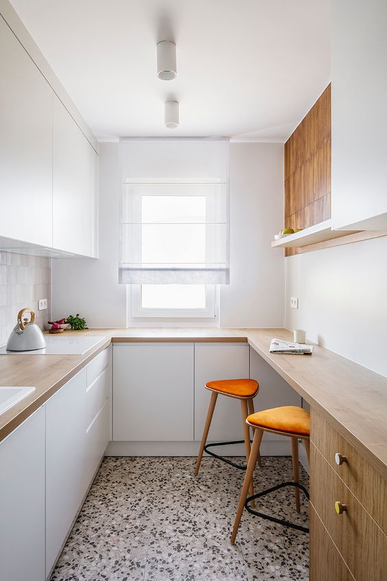 a small minimalist kitchen with sleek white cabinetry, butcherblock countertops and a bar counter for cooking and eating
