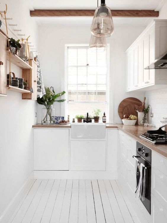 a small white Scandinavian kitchen with butcherblock countertops, a stained wooden shelf and wooden beams on the ceiling
