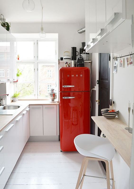 a small white kitchen in Scandinavian style, blonde wood countertops, a bold red fridge for a touch of color