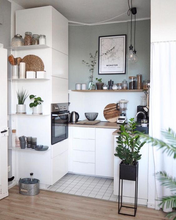 A tiny Scandinavian kitchen with sleek white cabinets, some open shelves and built in appliances plus pendant lamps