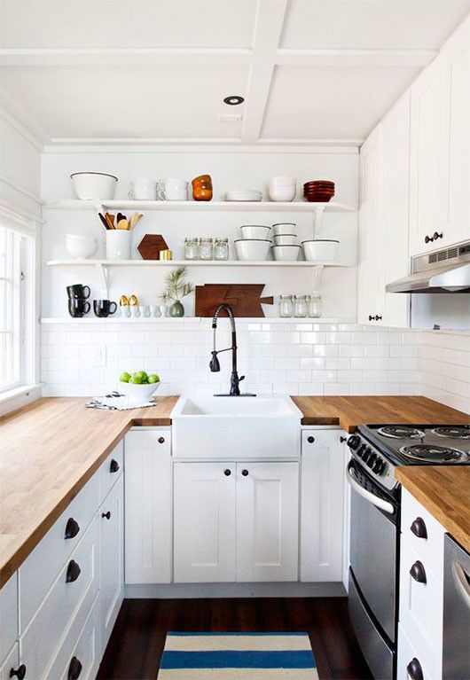 a white farmhouse kitchen with butcherblock countertops, open shelves and black handles and knobs
