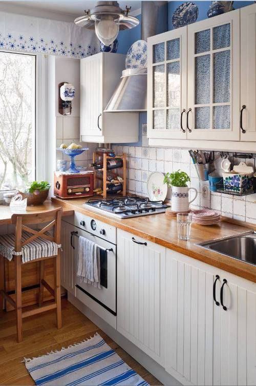 a white farmhouse kitchen with butcherblock countertops, tall stools and blue touches for coziness