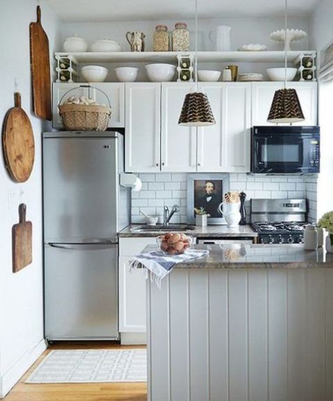a white farmhouse kitchen with subway tiles, a kitchen island and pendant lamps and wooden touches