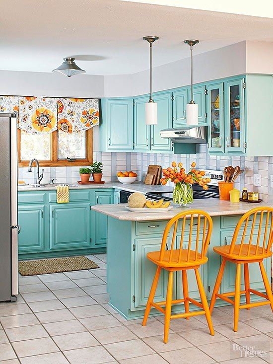 a bright blue kitchen with a tiled backsplash, orange chair, floral shades and retro lamps is a very cool idea
