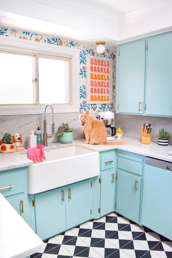 a bright blue kitchen with printed wallpaper, a colorful artwork and a tiled floor is fun and welcoming