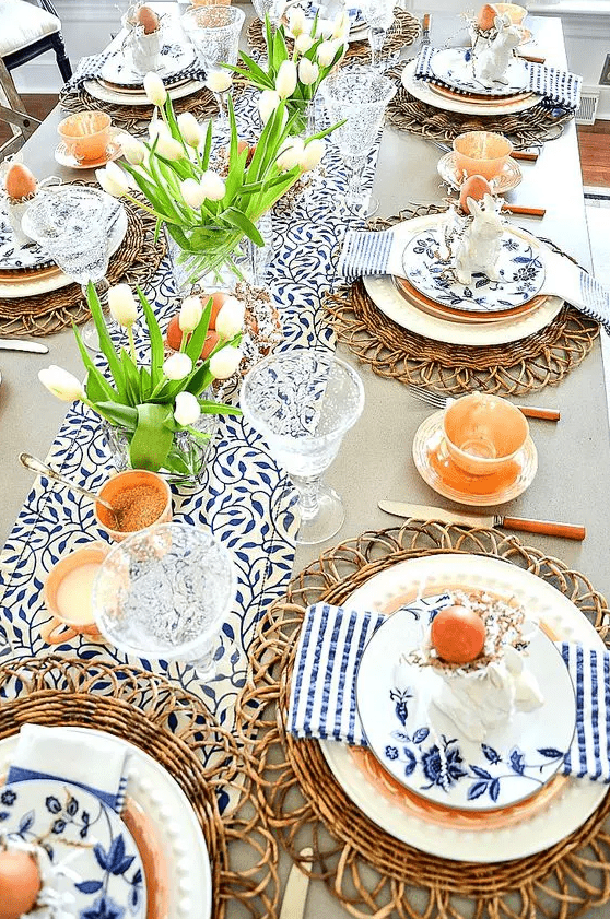 a bright rustic Easter tablescape with printed linens, rattan chargers, white tulips, candles and eggs plus floral plates