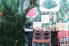 a bright tropical home office with tropical wallpaper, bright artworks and potted plants, a vintage desk and pink furniture