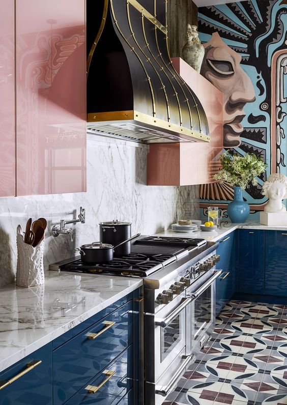 a colorful kitchen with navy lower cabinets, pink upper ones, a marble backsplash and a vintage hood to make a statement