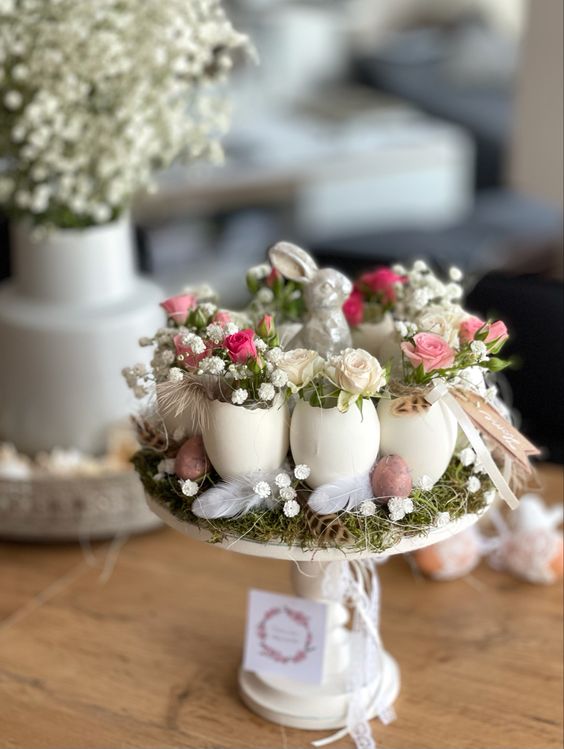 a creative Easter centerpiece with grass, feathers, baby’s breath, egg shellfs with dried blooms and a small bunny