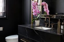a refined black powder room with matte walls, a black marble vanity, a large mirror, white appliances and pink orchids