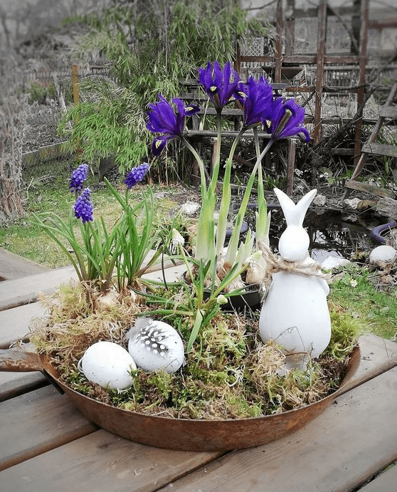a rustic Easter decoration of an old pan, moss, fake eggs and feathers, a bunny and fresh bulbs is amazing for outdoors
