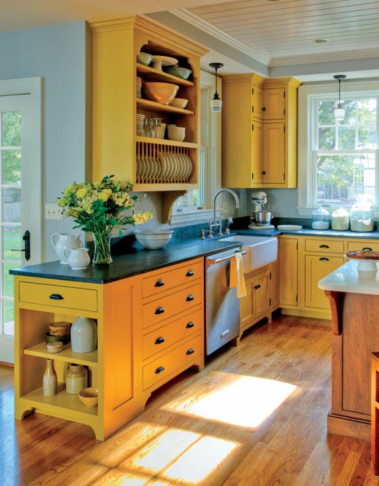 a sunny yellow kitchen with black coutnertops, a wooden kitchen island looks very inspiring, bold and cool