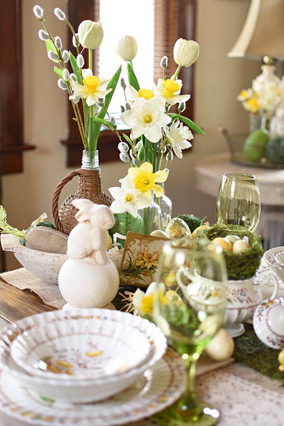 a vintage Easter centerpece of daffodils, tulips, willow, bunnies, moss and bowls and vases