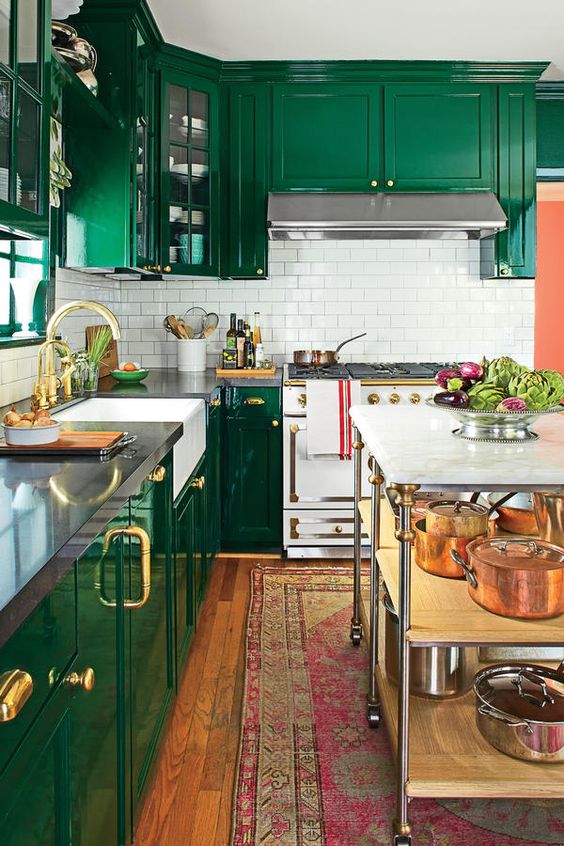 an emerald kitchen with a white subway tile backsplash, elegant gold touches and a bright boho rug
