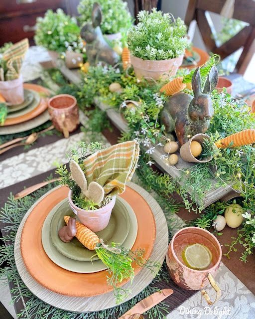 an organic Easter tablescape with lots of greenery, blooms, lights, bunny figurines and carrots and copper mugs