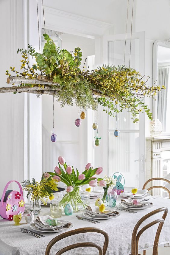 an overhead installation of branches, greenery, blooms and hanging eggs plus some spring blooms on the table are great for Easter tablescapes