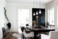a Scandinavian dining room with a chalkboard accent wall, a black table and white chairs, pendant lamps and faux fur