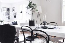 a chic dining space with a white dinin table and black chairs, a cool black chandelier, a potted plant and faux fur is cozy