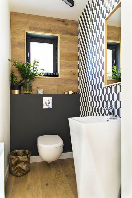 A chic guest toilet with a geometric wall, a plywood one, a blakc accent, a free standing sink and a fabric basket