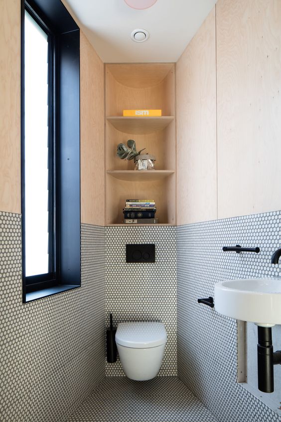 a contemporary guest toilet with a frosted glass window, penny tiles and plywood, with storage shelves and a wall-mounted sink