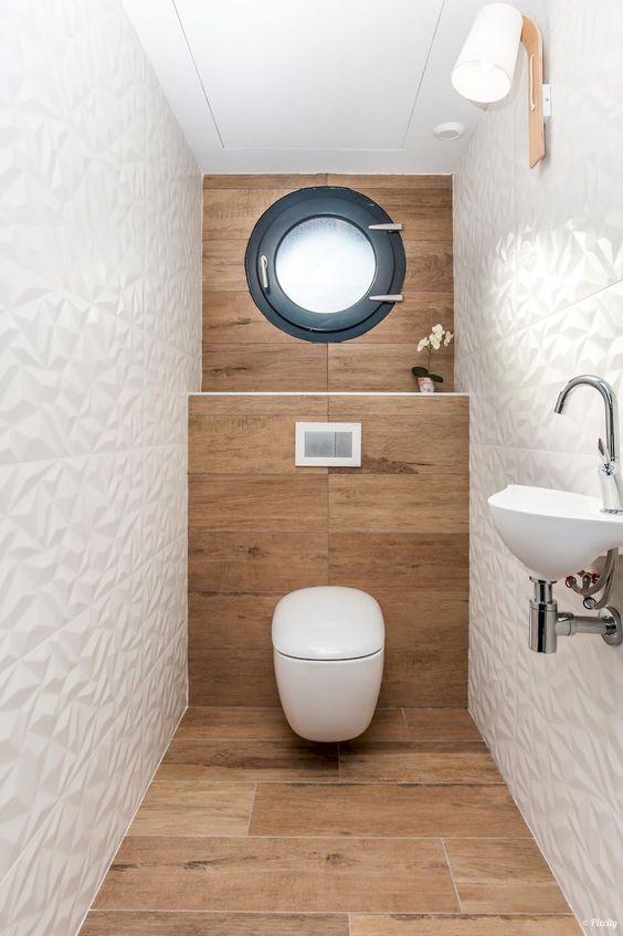 a contemporary guest toilet with wood-inspired tiles, geometric white ones, a window, a wall-mounted sink