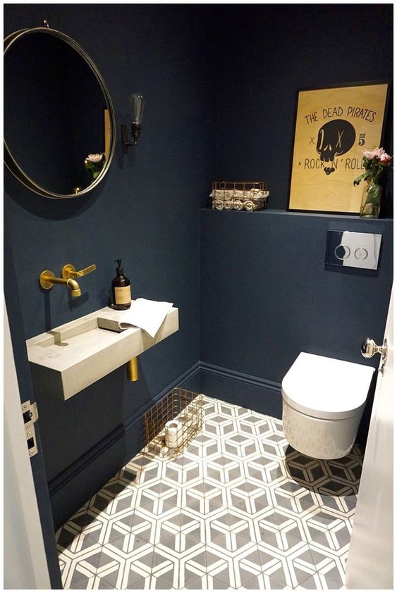 a cool guest toilet with navy walls, a geometric floor, an artwork and brass fixtures for a chic look