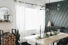 a farmhouse dining space with an accent wall, a stained table, black Eames chairs, a firewood stand and a black chandelier