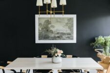 a laconic and welcoming dining room with a black accent wall, a white table and black chairs, an artwork and some greenery
