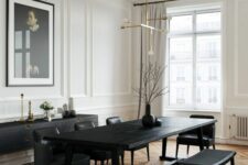 a refined black and white dining room with a black credenza, a black table and chairs, a modern chandelier and a statement artwork