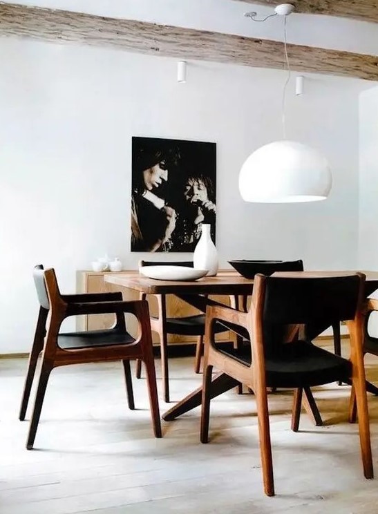 A refined yet simple mid century modern dining space with a stained table and black chairs, a chic credenza and a bold artwork
