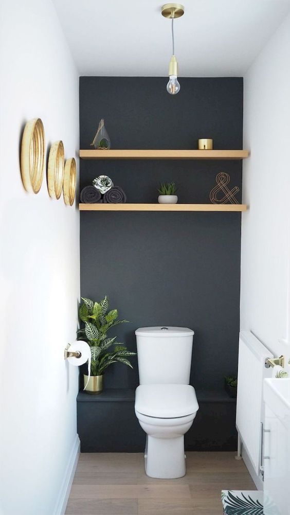 a small black and white guest toilet with a shelf, some gilded frame mirrors and a potted plant