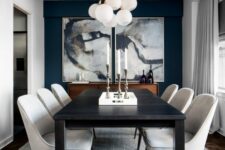 a sophisticated dining room with a black accent wall, a black table, off-white chairs, a neutral rug and a bubble chandelier