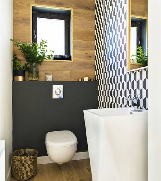 A tony guest toilet with a geometric wall, a free standing sink, a plywood and matte black wall plus a black framed window