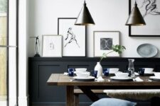 a welcoming black and white dining room with black paneling, a stained table and benches, a gallery wall and pendant lamps