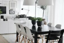 an airy Scandinavian dining room with a black table, white and black chairs, white pendant lamps and a pretty and very simple rug