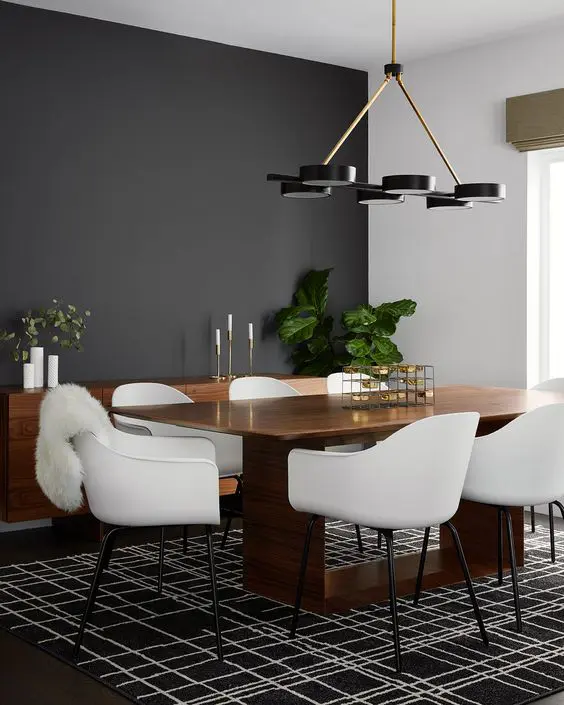 An elegant mid century modern dining room with a black accent wall, a stained table and a credenza, white chairs and a graphic rug