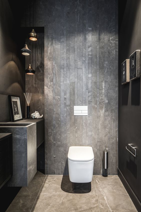 an industrial guest toilet done with concrete and stone, a cluster of pendant lamps, a stone sink and some art