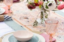 a colorful Mother’s Day table setting with printed napkins and runner, bold blooms and greenery, wicker placemats, pink glasses