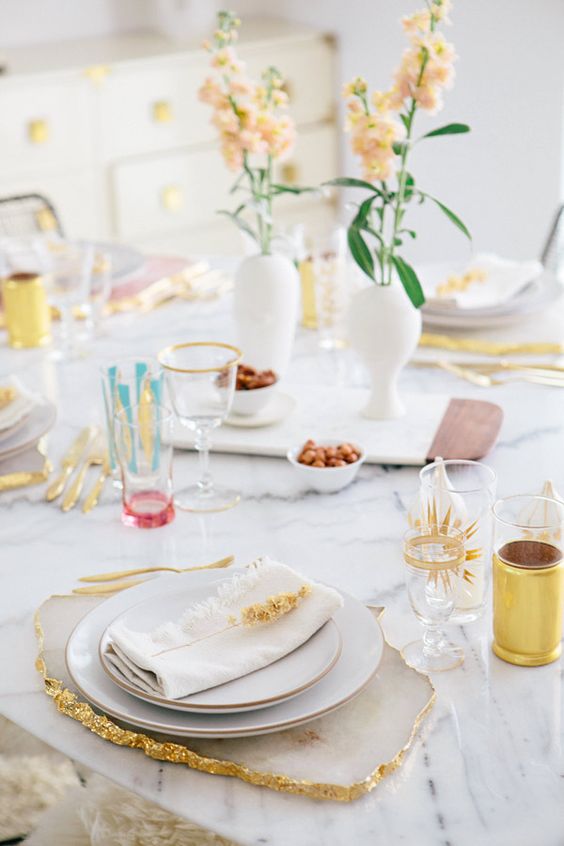 A pretty Mother's Day table setting with pastel blooms, geode placemats, gold rimmed plates and colorful touches