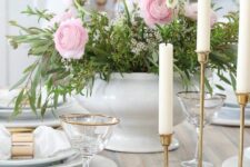 a refined Mother’s Day tablescape with pink and white blooms and greenery, white plates and napkins, tall and thin candles
