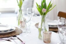 a simple and modern Mother’s Day tablescape with a white table runner, tulip centerpieces, wicker chargers and white porcelain