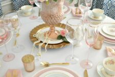 a vintage Mother’s Day tablescape with pink and blue plates, pink glasses and napkins and a pink floral centerpiece with pearls