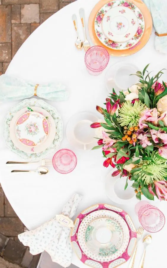 a vivacious Mother's Day tablescape with printed plates and pink glasses, pink and red blooms, printed napkins