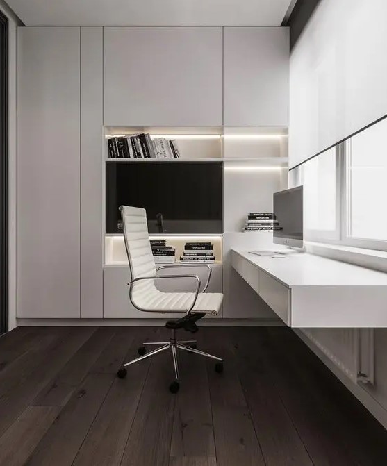 A refined minimalist home office with a large sleek built in storage unit with built in lights, a floating desk with storage, a chic white chair
