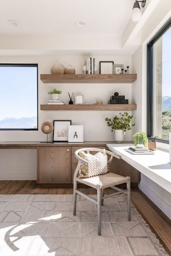 a welcoming neutral home office with amazing views and two desks, wooden shelves and a comfy chair, much natural light
