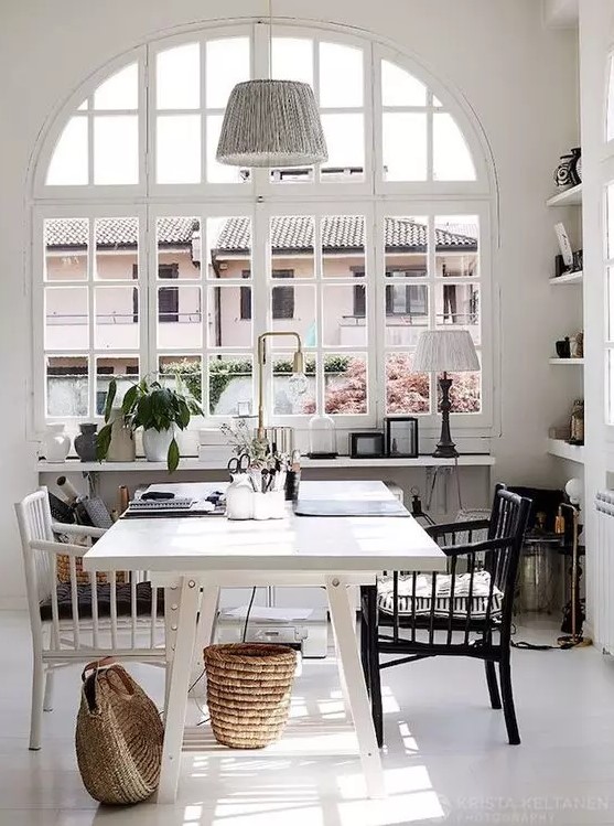 an airy Scandinavian home office with a white desk, a black and white chair, a pendant lamp, baskets and lamps is amazing