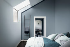 a small and minimalist attic bedroom done in moody blues and with teal and turquoise bedding